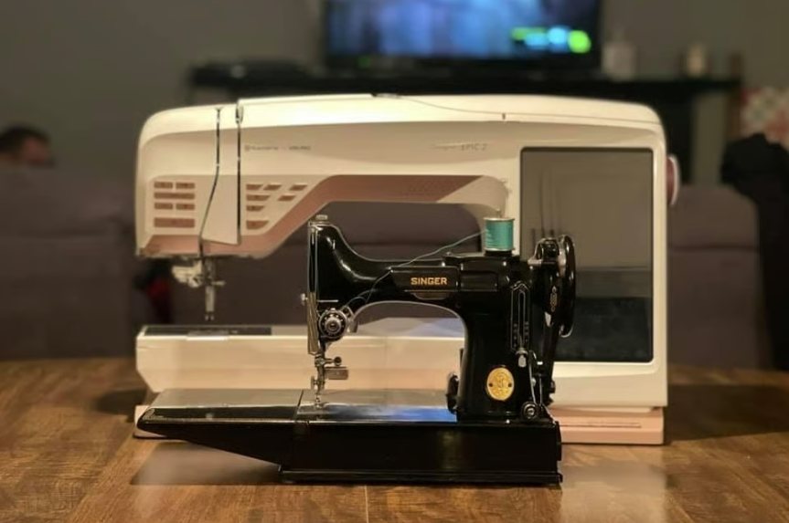 A vintage black Singer Featherweight sewing machine resting beside a modern computerized machine