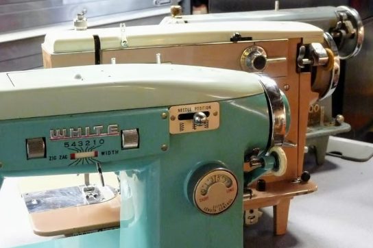 A seafoam green mid century White sewing machine on the repair bench